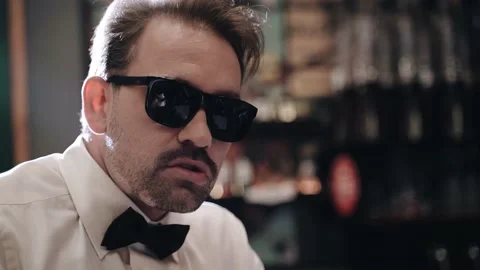 The tough guy is sitting at the bar and talking. He's wearing sunglasses Stock Footage 201969647