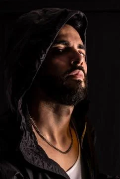 Tough man looking arrogant. Dramatic portrait of man wearing dark hood Stock Photos