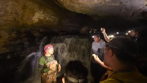 Tour guide explaining cave features to tourists exploring Jumandy Caverns 库存影片 334934671