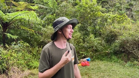 Tour guide holds microphone explaining rainforest ecosystem Stock Footage 346946359