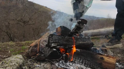 Tourist adding coal to the daytime campfire Stock Footage 238861644