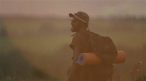 A tourist with a backpack and a camera at sunset in the field. Stock Footage 66259492
