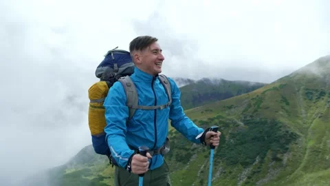 A tourist with a backpack climbed to the top and is happy with his success Stock Footage 218439349