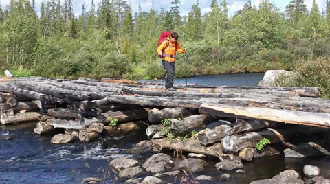 Tourist with a backpack crossing the river through the dilapidated wooden bridge Video stock 28684595