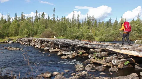 Tourist with a backpack crossing the river through the dilapidated wooden bridge Video stock 28684653