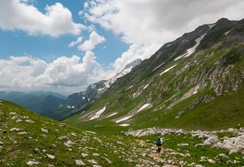 A tourist with a backpack descends from the pass down to the valley Stock Photos