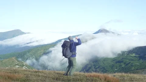 A tourist with a backpack is happy to conquer the mountain. Stock Footage 214326937
