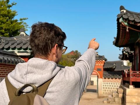 Tourist with a backpack points to the ancient Korean Palace Stock Photos