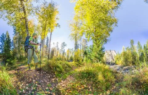 Tourist with a backpack walking through the forest with rocks Stock Photos