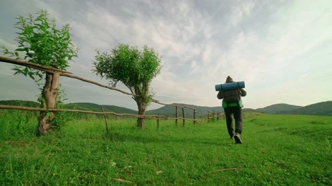 A tourist with a backpack walks along the path,in the background of the mountain 動画素材 198318751