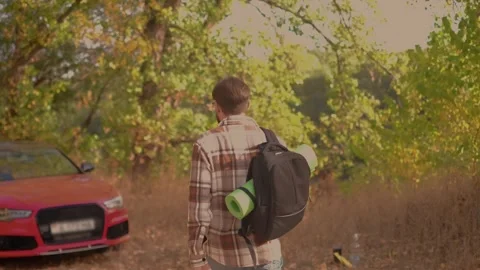 A tourist with a backpack walks away from the camera, wearing brown plaid shirt Stock Footage 278277320