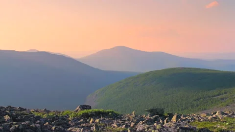 A tourist with a backpack walks in the mountains at sunset against the backdr Stock Footage 135371102