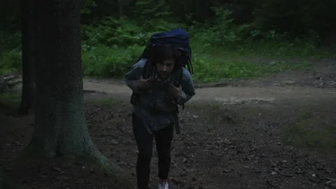 A tourist with a backpack walks through the night forest up the hill. Stock-Footage 201084187