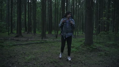 A tourist with a backpack walks through the night forest and looks around. Vidéo 201085059