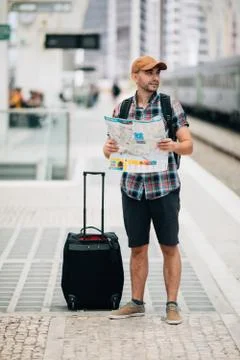 Tourist backpacker using map to travel at train station. Travel concept. Stock Photos
