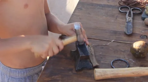 Tourist Boy is Using Hammer, Anvil, Rope During His Work with the Leather Stock Footage 58443024