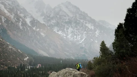 A tourist climbing to the top of a mountain with a backpack and trekking poles. Stock Footage 319639446