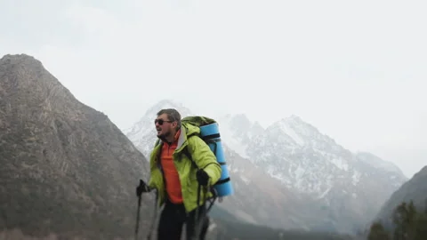 A tourist climbing to the top of a mountain with a backpack and trekking poles. Stock Footage 319639987