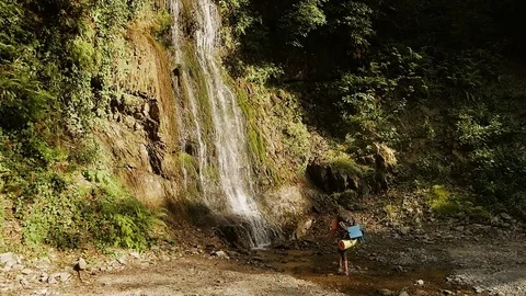 A tourist comes to a waterfall to have a drink Stock Footage