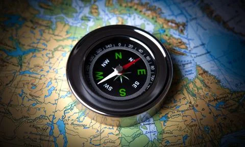 Tourist compass lying on a map Stock Photos