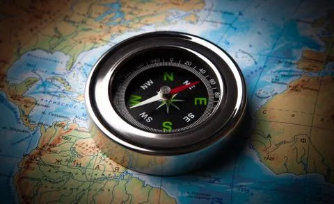 Tourist compass lying on a map Stock Photos
