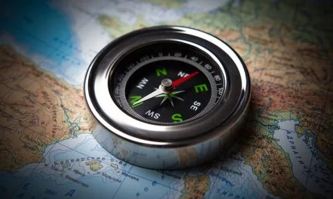 Tourist compass lying on a map Stock Photos