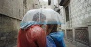 Tourist Couple Wearing Brightly Colored Poncho In Rainy European City Kissing Stock Footage