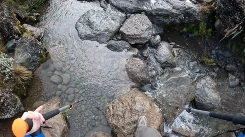 A tourist crosses a small stream over stones. First-person view Stock-Footage 169337666