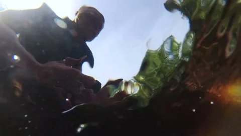 Tourist is drinking water from a mountain stream. View from under the water Stock Footage 80948504