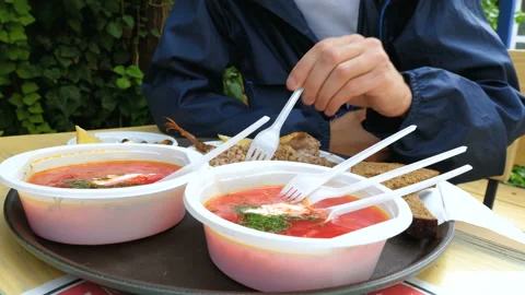 A tourist eats in an open-air summer cafe from plastic dishes. Video stock 97998733
