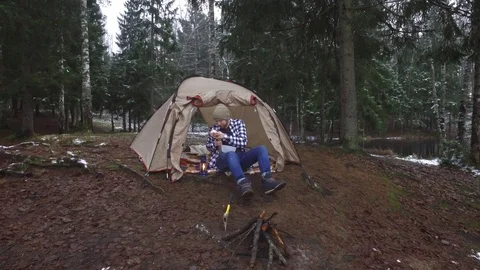 Tourist eats sandwiches while sitting in a tent on the lake shore Stock Footage 90132831