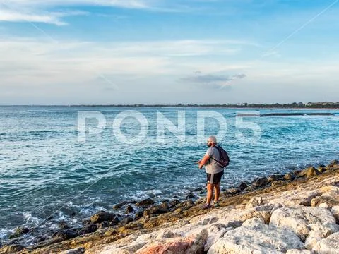 Tourist fishing off the beach in Kuta Bali Stock Photos