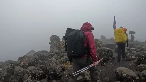 Tourist guy along with his guide and porters walk along a mountain path Vídeos de archivo 169337899