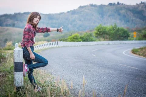 Tourist hitchhiking woman standing on the road in the mountains. Stock Photos