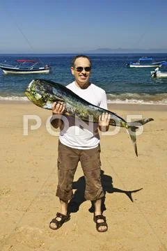 Tourist holding big fish on beach Stock Photos