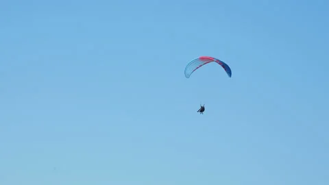 Tourist with instructor hovering in the sky on a paraglider. Tourist attraction Stock Footage 100067740