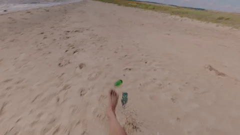 A tourist kicks a bottle on the beach. From the first person. 스톡 동영상 341347713