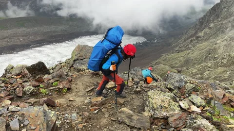 A tourist with a large backpack climbs up a mountain path Vídeo Stock 158159249