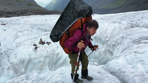 A tourist with a large backpack walks along the glacier 库存影片 158614111