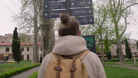 Tourist looking at arrows of pointer direction sign on post in Gulhane park Stock Footage 240745647
