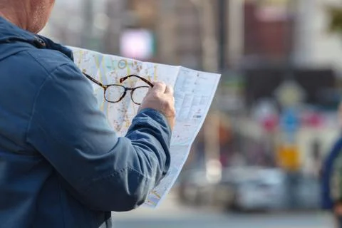 Tourist looking at the paper map instead phone. Positive emotion. Stock Photos