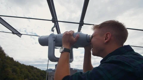 The tourist looks through the binoculars to the mountains. A man looks in a Video stock 97433853