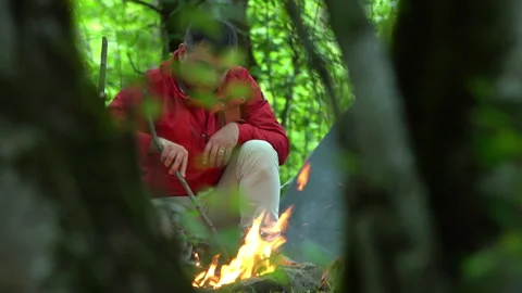 A tourist makes a fire with a stick while the camera pans 動画素材 310826598