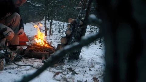 Tourist makes a fire in the winter forest near the reflector for a fire, Stock Footage 124641276