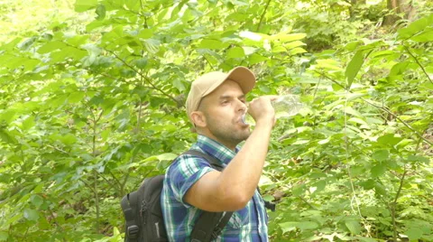Tourist man close-up walking through the forest drinks water. man with backpa Stock Footage 66524580