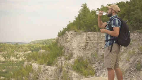 Tourist man close-up walking through the mountain drinks water. man with ba.. Stock Footage 73423064