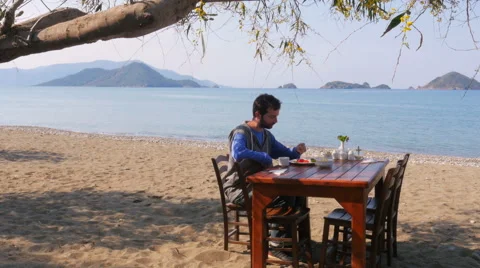 Tourist man eating, gorgeous breakfast beach with majestic sea background Video stock 51366053