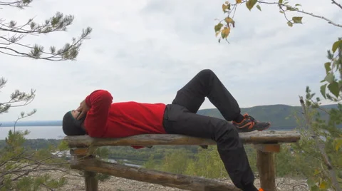 Tourist man He is lying on the bench in the mountains, and talking on the pho Stock Footage