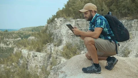 Tourist man He is sitting in the mountains, and using tablet . men with back Stock Footage
