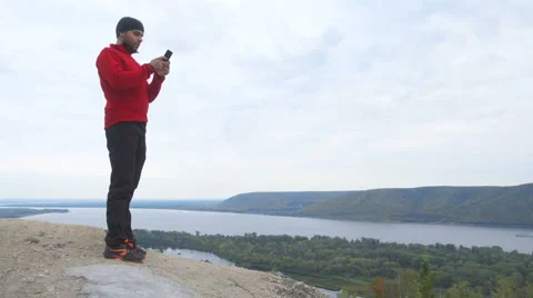 Tourist man He is standing in the mountains, and using smartphone . hiking. a Stock Footage